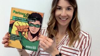 astendo-Mitarbeiterin hält das Verzeichnis "Partner der Verbände" in die Kamera